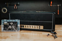 Guitar amplifier with a cassette tape and tools on a wooden surface