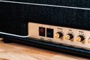 Close-up of a guitar amplifier with control knobs on a wooden surface