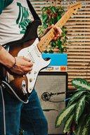 Person playing an electric guitar with a amplifier in the background