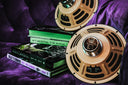 Gold guitar speaker on a purple surface with books underneath